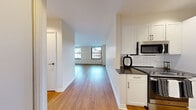 Located on Broad Street in Boston's historic Financial District, this one-bedroom, one-bathroom residence offers a well-designed layout across a single floor. Warm hardwood flooring runs throughout the unit, lending a cohesive and inviting feel to every room.

The kitchen is thoughtfully appointed with white shaker-style cabinetry, dark countertops, a classic white subway tile backsplash, and a full suite of stainless steel appliances including a range, microwave, dishwasher, and refrigerator. The space transitions naturally into an open corridor leading to the living area.

The living room is bright and airy, benefiting from multiple large windows that frame views of Boston's iconic surrounding architecture. The bedroom is generously proportioned, featuring a reach-in closet and large windows that allow ample natural light and city views.

The bathroom is clean and modern, with white tile surrounds in the tub/shower, a dark-countered vanity with white cabinetry, a medicine cabinet mirror, and neutral floor tiles.

Throughout the unit, the design aesthetic is clean and contemporary, with a neutral color palette, recessed lighting, and modern finishes that create a polished, move-in-ready environment in the heart of downtown Boston.