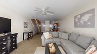 Located at 500 13th Street in Parkersburg, West Virginia, this two-story home offers three bedrooms, one bathroom, and a thoughtfully arranged layout spread across two floors. The main level features an open-concept kitchen and living room combination, where a ceiling fan overhead adds comfort to the spacious carpeted living area. The kitchen is equipped with warm wood cabinetry, granite-style countertops, black appliances including a range and refrigerator, and durable hardwood-style flooring. A staircase with open wood railings connects the two floors, adding a charming architectural element to the main living space. Upstairs, the bedrooms are bright and welcoming, each featuring hardwood floors and closets with sliding doors. The primary bedroom stands out with sliding glass doors that open to a private outdoor patio, allowing natural light to pour in. Additional bedrooms are cozy and well-proportioned, each with windows dressed in gray curtains. The single full bathroom is clean and functional, featuring a white vanity with under-sink storage, a mirrored medicine cabinet, and wood-look flooring. With three closets distributed throughout, the home offers ample storage. The overall ambiance is light, neutral, and move-in ready.