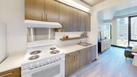 Located at 200 Folsom Street in San Francisco's vibrant SoMa neighborhood, this one-bedroom, one-bathroom residence offers a well-designed single-floor layout with contemporary finishes throughout. The space features light wood-tone flooring that runs continuously through all rooms, creating a cohesive and clean aesthetic.

The kitchen is equipped with warm wood cabinetry extending to the ceiling, light quartz countertops, a stainless steel sink, an electric range, and a full-size refrigerator. A floating wood shelf adds a functional decorative touch, and under-cabinet lighting illuminates the workspace efficiently.

The bedroom showcases a distinctive exposed concrete ceiling that adds an industrial character, paired with crisp white walls for balance. A large floor-to-ceiling window brings in natural light and connects the room to city views. The bedroom opens directly into the hallway, which leads to both the living area and the bathroom.

The bathroom is spacious relative to the overall footprint and is designed with accessibility in mind, featuring stainless steel grab bars, a shower with a curtain enclosure, a wood-toned vanity, and the same light hardwood flooring found throughout the unit.

The living area benefits from expansive floor-to-ceiling windows that flood the space with natural light, offering views of the surrounding cityscape. Overall, the residence presents a modern, urban aesthetic with practical and thoughtfully integrated design elements.