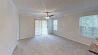 This single-floor residence in Riverdale, Georgia offers a thoughtfully designed layout that balances comfort and practicality. The living area features plush carpeting, crown molding, and a ceiling fan with light fixture, while sliding glass doors invite natural light and provide outdoor access. An adjacent dining area is accented with a chandelier and chair-rail molding along soft gray walls, creating a refined yet welcoming atmosphere.

The kitchen is efficiently arranged with white cabinetry, granite-look countertops, stainless steel appliances including a dishwasher and range, and a full-size refrigerator. Wood-look flooring runs throughout the kitchen and dining spaces, offering both durability and style. A peninsula counter provides additional prep space and a natural divide between the kitchen and dining area.

The bedroom is a calm, carpeted retreat featuring a spacious walk-in closet with double doors and direct access to the bathroom. A large window frames outdoor greenery, filling the room with natural light. The bathroom is well-appointed with a granite countertop vanity, white cabinetry, an undermount sink, and a well-lit mirror. A second carpeted bedroom with a large window offers views of the surrounding landscape. This residence combines practical design with quality finishes throughout.