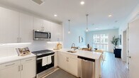 Located at 6461 US-9 N in Howell, NJ, this two-bedroom, one-bathroom residence offers a thoughtfully designed open-concept layout across a single floor. The kitchen is a standout feature, boasting white shaker cabinetry, a classic subway tile backsplash, white quartz countertops, and a full suite of stainless steel appliances including a gas range, built-in microwave, dishwasher, and refrigerator. Stylish pendant lighting illuminates the kitchen island, which flows seamlessly into the combined dining and living area. The living room is bright and airy, filled with natural light from a sliding glass door that opens to a private balcony with an exterior view. Light wood-tone flooring runs throughout the main living areas, complementing the clean, neutral color palette. The primary bedroom offers a comfortable footprint with ample wall space and closet storage featuring built-in shelving. The second bedroom provides additional flexibility. The shared bathroom is finished with large-format tile flooring, a wide vanity with light wood cabinetry, and a full-width mirror. A welcoming entryway with additional storage rounds out this efficiently designed and modern home.