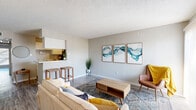This thoughtfully laid-out one-bedroom, one-bathroom unit offers a functional and welcoming living experience across a single floor. The open-concept living and kitchen area forms the heart of the home, bathed in natural light from a large sliding door that brightens the space. The living area features wood-look flooring, a textured ceiling, and neutral grey walls that create a clean, modern backdrop. A galley-style kitchen runs adjacent to the living space, equipped with white cabinetry, light countertops, black appliances including a refrigerator and electric range, and a pass-through counter with bar seating that connects seamlessly to the living room. A hallway with decorative wall accents leads to the private quarters of the unit. The spacious primary bedroom comfortably accommodates a full-sized bed and includes a dedicated walk-in closet, providing ample storage. Additional closets are available elsewhere in the unit, totaling three in all. The full bathroom is finished with wood-look flooring, a tub-shower combination, and a vanity with countertop space. Throughout the unit, consistent flooring and a cohesive neutral color palette contribute to a unified, modern aesthetic that is both practical and inviting.