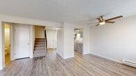 This two-story unit at 2309 East Euclid Avenue in Spokane, Washington offers a well-organized layout spread across two floors. The main level features an open living area with light wood-style vinyl flooring, a ceiling fan, baseboard heating, and a wall-mounted air conditioning unit. Multiple windows allow natural light to fill the space, creating a bright and welcoming atmosphere. A carpeted staircase connects the two levels, with a convenient entry door accessible from the main floor. The kitchen is efficiently designed with grey cabinetry, white subway tile backsplash, light countertops, and black appliances including an electric range and refrigerator. A double sink and overhead lighting complete the functional cooking space, which opens toward the living area for a connected feel. The upper level hosts carpeted bedrooms, each featuring built-in closets with shelving and rods for storage, along with windows that bring in natural light. The bathroom includes a full tub-shower combination, toilet, and vanity with tile-style flooring. Throughout the unit, a neutral color palette of whites and soft grays provides a clean, move-in-ready aesthetic suited for comfortable everyday living.