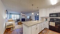 This well-appointed 2-bedroom, 2.5-bathroom single-floor residence offers a thoughtfully designed open-concept layout that seamlessly connects the kitchen, dining, and living areas. The kitchen is a standout feature, showcasing granite countertops, crisp white cabinetry with brushed nickel hardware, a large center island with bar seating, and pendant lighting that adds a warm, modern touch. The living room is bright and inviting, with large windows dressed in plantation shutters and sheer curtains that allow generous natural light. A fireplace serves as a focal point, while rich hardwood-style flooring flows throughout the main living areas, adding warmth and continuity.

Each bedroom offers a comfortable, carpeted retreat with ceiling fans, ample natural light, and well-sized windows. The primary bedroom connects to a private en-suite bathroom featuring granite countertops, white cabinetry, and a clean, modern aesthetic consistent with the rest of the home. A second full bathroom mirrors the same refined finishes, and a convenient half bath completes the layout.

Throughout the residence, a cohesive neutral color palette paired with textured ceilings creates a welcoming ambiance, making this a functional and attractive space suited for everyday living.