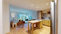 Located at 1315 Adams St in Nashville, TN, this thoughtfully designed one-bedroom, one-bathroom residence offers a cohesive modern aesthetic across its single-floor layout. Light-toned hardwood flooring flows throughout, unifying each space with warmth and continuity.

The open-concept kitchen and living area serves as the heart of the home. The kitchen is outfitted with natural wood cabinetry, open shelving, a tiled backsplash, stainless steel appliances including a gas range and French door refrigerator, and a central island with seating — ideal for both cooking and casual dining. Recessed lighting illuminates the space efficiently.

The living room benefits from a dramatic floor-to-ceiling window that frames views of the surrounding Nashville streetscape and greenery, flooding the room with natural light. The layout comfortably accommodates a full seating arrangement, anchored by the expansive window as a focal point.

The bedroom is a calm, well-proportioned retreat featuring a corner window with outdoor views, a double closet, and clean white walls. A hallway connects the bedroom to the full bathroom, which features a light wood vanity with a white countertop, a large black-framed mirror, matte black fixtures, and a tiled walk-in shower. Terrazzo-style flooring completes the bathroom's refined, contemporary finish.