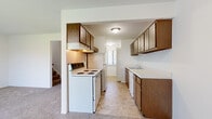 This two-story residence presents a straightforward and functional layout across both levels. The kitchen serves as a practical hub, featuring warm wood-toned cabinetry on both upper and lower sections, light countertops, a stainless steel sink, a white electric coil range with overhead ventilation, a dishwasher, and a refrigerator. Tile flooring runs throughout the kitchen, which opens toward an adjacent area, creating an easy flow between spaces. A staircase connects the two floors, visible from the kitchen area.

The bedrooms are carpeted and finished with neutral white walls, lending a clean and versatile atmosphere. Each room includes closet space, with some featuring sliding or hinged closet doors. One bedroom offers access to what appears to be an en-suite or walk-in closet arrangement, while a separate bedroom includes a standard reach-in closet. Large windows with vertical blinds allow natural light to filter into the living areas.

The bathroom is clean and functional, featuring tile flooring, a single-sink vanity with wood cabinetry, a large wall mirror, and a tub-shower combination. Overall, the space maintains a simple, neutral aesthetic with practical finishes throughout.