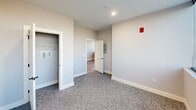 Located at 1230 Elm St in Manchester, NH, this 2-bedroom, 1-bathroom unit offers a thoughtfully designed layout with modern finishes throughout. The kitchen is a standout feature, equipped with white shaker cabinets, quartz countertops, a subway tile backsplash, stainless steel appliances — including a range, microwave, and refrigerator — and wood-look luxury vinyl plank flooring. Pendant lighting adds a polished touch above the sink and counter area. Both bedrooms are carpeted and bathed in natural light from large, floor-to-ceiling corner windows that frame expansive views of the Manchester cityscape and surrounding hills. Each bedroom includes its own dedicated closet with built-in shelving, providing practical storage. The bathroom is clean and contemporary, featuring wood-look flooring, a white vanity with a single sink, matte black fixtures, and a full tub-shower combination. Neutral gray walls and white trim are consistent throughout the unit, creating a cohesive and modern aesthetic. The overall ambiance is bright, clean, and move-in ready, making it an ideal urban residence in the heart of Manchester.