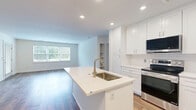 Located at 138 Mt Auburn Ave in Auburn, Maine, this well-appointed 2-bedroom, 1-bathroom home offers a clean, modern aesthetic across a single thoughtfully designed floor. The open-concept kitchen and living area serves as the heart of the home, anchored by a central island with a undermount sink and white quartz countertops. Crisp white shaker-style cabinetry lines the kitchen walls, complemented by a full suite of stainless steel appliances including a range, microwave, dishwasher, and refrigerator. Recessed lighting illuminates the space, while warm hardwood-style flooring flows throughout the main living areas. The spacious living room features large windows and a glass-panel door that invite abundant natural light and outdoor views. The generously sized primary bedroom offers plush carpeting, a large window with outdoor views, and access to a well-sized closet with wire shelving for organized storage. The second bedroom mirrors this comfortable layout with carpet flooring and natural light. The full bathroom is finished with classic black-and-white mosaic tile flooring, a white vanity with brushed nickel fixtures, and a full tub-shower combination. Two hallways connect the rooms efficiently, and additional closet space adds practical storage throughout.