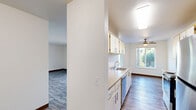 Located at 380 NW Gina Way in Beaverton, Oregon, this single-floor, two-bedroom, two-bathroom residence offers a practical and well-organized layout with consistent finishes throughout. The galley-style kitchen is efficiently designed with ample white cabinetry featuring gold-trimmed accents, beige laminate countertops, stainless steel appliances including a range, dishwasher, and refrigerator, and wood-look flooring that carries a warm, clean aesthetic. Adjacent to the kitchen, the dining area benefits from multiple windows that bring in natural light and offer views of surrounding greenery, complemented by a ceiling fan for added comfort. The living room continues the wood-look flooring and provides an open, versatile space. Both bedrooms are carpeted and well-sized, with the primary bedroom offering a comfortable footprint and natural light from a large window. The secondary bedroom also features a window with outdoor views. The two bathrooms are finished with wood-look tile flooring, single-sink vanities with beige countertops, and well-lit mirrors with overhead lighting fixtures. The overall aesthetic throughout is clean, neutral, and functional, making this a straightforward and accessible residence in the Beaverton area.