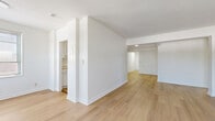 Located at 112 Hoyt St in Stamford, CT, this two-bedroom residence offers a clean, modern aesthetic across a well-organized single-floor layout. Light-toned hardwood flooring runs continuously throughout, creating a cohesive and bright atmosphere in every room.

The combined living and dining area serves as the heart of the home, featuring multiple windows with classic blinds that invite natural light while offering views of the surrounding greenery. Baseboard radiators provide reliable heating throughout the space.

The galley-style kitchen is efficiently laid out with white cabinetry, a stainless steel refrigerator, gas range, dishwasher, and an over-range microwave. A window above the sink allows for natural light during meal preparation.

Both bedrooms are well-proportioned, with the spacious primary bedroom offering ample room for furnishings. Each bedroom benefits from natural light through large windows. Notably, the space includes six closets, providing exceptional storage throughout.

The bathroom is a standout feature, showcasing floor-to-ceiling bold navy blue square tiles contrasted by a white soaking tub and a frosted privacy window, creating a striking visual impact.

A hallway connects the rooms with ease, and the overall design is defined by crisp white walls, clean lines, and a bright, minimalist sensibility throughout.