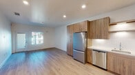 Located at 1692 Sycamore Dr in Simi Valley, California, this single-floor unit offers a clean, modern aesthetic with thoughtfully designed living spaces. The open-concept layout seamlessly connects the kitchen and living area, creating a bright and functional space bathed in natural light from large windows and a glass door that opens to a balcony with neighborhood views. Recessed lighting throughout enhances the airy atmosphere.

The kitchen is well-appointed with warm wood-toned cabinetry extending to the ceiling for ample storage, crisp white countertops, and a full suite of stainless steel appliances including a refrigerator, electric range, microwave, and dishwasher. Light hardwood-style flooring runs throughout the main living areas, contributing to the unit's contemporary and cohesive feel.

The bedroom is a comfortable retreat, featuring plush carpeting, a bright window with natural light, and access to a dedicated walk-in closet with built-in shelving. The bathroom maintains the same modern design language, showcasing wood-toned cabinetry, a white vanity countertop, a large mirror, and hardwood-style flooring. The clean white walls and neutral palette throughout the unit provide a versatile backdrop, making this a well-rounded and move-in-ready space.