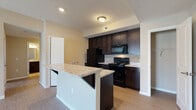 Located at 3785 Codet Road in Columbus, Ohio, this single-floor residence offers a thoughtfully designed open-concept layout. The kitchen serves as a central highlight, showcasing rich dark espresso cabinetry that extends to the ceiling for ample storage, light granite-look countertops, and a full suite of black appliances including a refrigerator, electric range, and over-the-range microwave. A peninsula with a double-basin sink and breakfast bar seating seamlessly connects the kitchen to the living area, making it ideal for both cooking and entertaining. The flooring transitions from warm wood-look planks in the kitchen and entryway to plush carpet in the living area, creating a comfortable and cohesive feel throughout. The living space is generously sized, with neutral warm-toned walls and a sliding glass door that opens to a private balcony, allowing natural light to fill the room and providing views of the surrounding neighborhood. A walk-in closet offers convenient and practical storage. The bathroom features a full tub-shower combination with built-in shelving, tile-look flooring, and clean, bright finishes. The overall ambiance of this residence is clean, modern, and functional, offering a comfortable living environment in an accessible Columbus location.