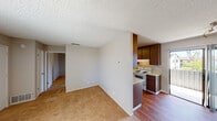 This single-floor residence offers a practical and comfortable layout designed for everyday living. The main living area is generously sized, featuring warm beige carpet that transitions to hardwood-style flooring, neutral taupe walls, and a textured popcorn ceiling throughout. Large vertical-blind windows allow natural light to fill the space, creating a bright and open atmosphere.

The kitchen is efficiently designed with rich, dark wood cabinetry offering ample storage, light-toned countertops, a white electric range, a full-size refrigerator, and a sink with a window view. Hardwood-style flooring extends through the kitchen, and a sliding door provides direct access to the outdoors.

The bedroom is a well-proportioned, carpeted retreat with a window fitted with vertical blinds and a sliding closet for convenient storage. The entry area connects seamlessly to the rest of the unit, with multiple doors providing access to the hallway and additional rooms.

The bathroom features a clean, all-white tub and shower combination with chrome fixtures, complemented by hardwood-style flooring. Overall, the unit presents a straightforward, functional design with consistent neutral finishes and adequate natural light throughout.