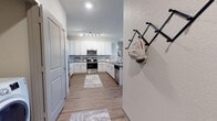 This single-floor residence offers a thoughtfully designed layout that balances functionality with contemporary style. The entry foyer welcomes you with wood-look flooring that extends throughout the main living areas, and a wall-mounted rack provides a practical first impression.

The kitchen is a standout feature, offering generous cabinetry in crisp white with brushed nickel hardware, dark gray countertops, and a full suite of stainless steel appliances including a range, microwave, and refrigerator. A track lighting system overhead ensures the space is well-lit, and the open layout connects seamlessly to the rest of the home.

The living room is bright and inviting, lined with multiple large windows dressed in decorative curtains and blinds that allow abundant natural light to fill the space. A ceiling fan adds both function and charm to this comfortable gathering area.

The bedrooms feature plush carpeting and large windows that bathe each room in natural light. The primary bedroom includes access to a walk-in closet with built-in shelving and hanging rods, offering ample storage. Both bathrooms are finished with white cabinetry, dark countertops, undermount sinks, and tub-shower combinations with tile surrounds, maintaining a clean and cohesive aesthetic throughout.