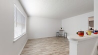 Located at 295 Creekside Dr. in Jeffersonville, Indiana, this two-story, 2-bedroom, 1-bathroom home offers a clean, modern aesthetic spread across two well-proportioned floors. The main level features light wood-look flooring throughout the living room and kitchen, complemented by crisp white walls and a textured ceiling. The bright living room benefits from natural light through blinds-fitted windows and connects seamlessly to the kitchen. The kitchen is well-appointed with slate-gray shaker cabinetry, light countertops, stainless steel appliances including a range, dishwasher, and refrigerator, plus a ceiling fan overhead. A spacious closet with louvered bi-fold doors provides additional storage on this level. Upstairs, both bedrooms are finished with plush carpeting and ceiling fans. The primary bedroom includes a large louvered bi-fold closet and ample space, while the second bedroom features a natural light window and its own closet access. The upper level is connected by a staircase with a classic metal railing. The shared full bathroom features a tiled tub-shower combination, a window for natural light, and clean white finishes throughout. The home's consistent gray-accented doors and trim create a cohesive, contemporary look.