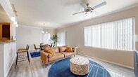 This single-floor residence offers a thoughtfully designed open-concept layout that seamlessly connects the living, dining, and kitchen areas. The living room is bright and welcoming, featuring crown molding, a ceiling fan, light wood-style flooring, and large windows fitted with vertical blinds that invite generous natural light. A sliding glass door provides access to the outdoors, further enhancing the airy ambiance of the space.

The dining area flows naturally from the living room and is anchored by an elegant chandelier, with crown molding continuing the refined architectural detailing throughout. The kitchen is equipped with dark espresso cabinetry, granite countertops, stainless steel appliances, and track lighting overhead. A breakfast bar with seating offers a convenient casual dining option.

The primary bedroom is a serene retreat, bathed in natural light through multiple windows, and features the same wood-style flooring found throughout the home. The en-suite bathroom includes dual sinks set in granite countertops, dark cabinetry, a large mirror with vanity lighting, and a tub-shower combination. A second bedroom provides comfortable accommodations with a ceiling fan and a spacious sliding-door closet. A second full bathroom mirrors the quality finishes of the primary bath.
