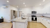Located at 102 E Farwell in Spokane, WA, this well-appointed 2-bedroom, 2-bathroom residence offers a thoughtfully designed single-floor layout with a clean, contemporary aesthetic throughout. Light wood flooring flows seamlessly across all rooms, complemented by bright white walls and recessed lighting that create an airy, welcoming atmosphere.

The open-concept kitchen and living area serves as the heart of the home. The kitchen is outfitted with crisp white shaker cabinets, sleek gray countertops, a center island with a single-basin sink and a matte black pull-down faucet, and a full suite of stainless steel Whirlpool appliances, including a refrigerator, electric range, and over-the-range microwave. An in-unit laundry area is also conveniently accessible nearby. The adjacent living room is bright and inviting, with windows and a glass-panel door providing natural light and outdoor access.

The spacious primary bedroom features multiple windows with views of the surrounding area, flooding the room with natural light. The second bedroom is equally well-lit and comfortable. Both rooms are served by dedicated closets, including a generous walk-in closet with wire shelving. The two bathrooms are finished with clean white fixtures, matte black hardware, and a tub-shower combination, maintaining the home's consistent modern style.