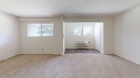 Located at 5950 Westower Ct in Richmond, Virginia, this single-floor unit offers a clean, functional layout designed for comfortable everyday living. The interior is finished with a neutral color palette throughout, creating a bright and cohesive atmosphere.

The galley-style kitchen features wood-look plank flooring, light-toned countertops, white cabinetry with brushed nickel hardware, and includes appliances such as a full-size refrigerator and dishwasher. Ample counter space on both sides of the kitchen provides a practical workspace for meal preparation.

The living and sleeping areas are carpeted with plush, neutral-toned carpet and benefit from multiple windows that invite natural light and offer views of surrounding greenery. Sliding closet doors provide generous built-in storage, and a wall-mounted HVAC unit ensures climate comfort year-round.

The bathroom is divided into two functional zones: a private water closet with a bathtub and toilet featuring wood-look flooring, and a separate vanity area with a wide countertop sink, white cabinetry with brushed nickel accents, and a large wall mirror framed by overhead lighting. The overall design is clean and practical, making this a well-organized and move-in-ready space.