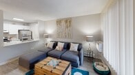 This single-floor residential unit offers a thoughtfully designed layout that maximizes functionality and comfort throughout. The galley-style kitchen is outfitted with crisp white cabinetry, marble-look countertops, stainless steel appliances including a full-size refrigerator, an electric range, and a deep sink — all set against light wood-look flooring that flows consistently through the space.

The living area is bright and welcoming, featuring a large window with vertical blinds that allows natural light to fill the room. A textured ceiling adds a classic touch, while the open feel of the space comfortably accommodates seating and a sitting area arrangement.

The two bedrooms are well-proportioned, each with windows that invite natural light, vertical blinds, wood-look flooring, and textured ceilings. Both rooms include built-in closet storage, offering practical organization solutions.

The bathroom is divided into two connected areas — a vanity zone featuring a white cabinet with a marble-look countertop, an illuminated mirror, and a sink, which leads into a separate wet area with a shower-tub combination. The neutral gray and white color palette used throughout the unit creates a clean, cohesive aesthetic that is both modern and inviting.