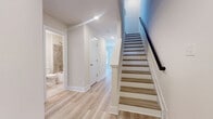 Located at 1801 Guilford Ave in Baltimore's Midtown neighborhood, this thoughtfully designed three-bedroom, four-bathroom home spans three floors, offering a well-organized layout with generous living space. Light wood-tone flooring flows consistently throughout, complementing the neutral, warm white walls that create a bright and clean aesthetic across every level.

The main floor features an open-concept kitchen and living area filled with natural light from large windows. The kitchen is a standout, showcasing a two-tone design with dark lower cabinetry, white upper cabinets, a classic subway tile backsplash, stainless steel appliances, and a large center island with a white countertop, undermount sink, and pendant lighting above.

A convenient half bath with wood flooring and brushed gold fixtures is also found on this level. The hallways are well-lit with recessed lighting, and a staircase with a dark handrail connects all three floors. One of the full bathrooms features floor-to-ceiling neutral tile surrounding a soaking tub, while another half bath offers a minimalist design with a wall-mounted sink.

The three bedrooms are spread across the upper floors, each with light wood flooring. The primary bedroom is a comfortable retreat, while secondary bedrooms offer views of the surrounding Baltimore streetscape through large windows with ceiling fans for added comfort.