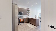 Located at 610 Jerry St in Castle Rock, CO, this thoughtfully designed one-bedroom, one-bathroom residence offers a modern aesthetic across a single, efficiently organized floor. Light wood-tone flooring flows throughout the main living areas, anchoring the clean, contemporary style.

The kitchen is a standout feature, equipped with stainless steel appliances including a range, microwave, and dishwasher. Rich dark wood cabinetry is paired with crisp white quartz countertops and a classic white subway tile backsplash. Open floating shelves add a stylish, functional touch, while a peninsula with a sink creates a natural transition into the dining area.

The living room is bright and welcoming, with large windows that invite abundant natural light and provide outdoor views. A glass door leads to the private balcony, extending the living space outdoors.

The bedroom is a comfortable retreat featuring a large window with views of the surrounding neighborhood, soft carpet flooring, and a dedicated closet. The bathroom is finished with clean white tile, a soaking tub with a rain showerhead, and a wood-accented vanity with white countertop.

Additional practical spaces include a hallway, utility room, and in-unit laundry, making this a fully equipped and functional home in a modern Castle Rock community.