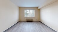 This 360 square foot studio apartment in Gresham, Oregon, offers a thoughtfully designed living space on a single floor. The open-concept layout combines the kitchen and living area, creating a sense of spaciousness despite the compact footprint. 

The living area features light-toned wood-look flooring and is illuminated by a large window that allows natural light to flood the space. A wall-mounted heating and cooling unit provides climate control.

The kitchen is modern and functional, boasting white cabinetry, stainless steel appliances including a full-size refrigerator, range, dishwasher, and over-the-range microwave. Track lighting overhead ensures ample illumination for meal preparation.

The bathroom, while compact, is efficiently designed with a full-size bathtub and shower combination, a toilet, and necessary fixtures. Light-colored tiles and walls contribute to a clean, bright appearance.

Throughout the apartment, neutral wall colors and minimalist design create a blank canvas for personalization. The layout maximizes every square foot, making this studio an ideal option for those seeking a low-maintenance, modern living space in a convenient location.