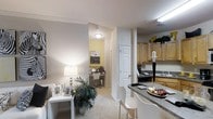 Located at 101 Crossing Dr in Millbrook, Alabama, this single-floor residence offers a well-designed, open-concept layout that seamlessly connects the primary living spaces. The kitchen is outfitted with warm honey-toned wood cabinetry, dark granite countertops, and a built-in cooktop, with an extended breakfast bar providing casual seating and a natural transition into the living area. The living space features plush carpeting, crown molding, and soft neutral tones that create a welcoming ambiance, complemented by warm lamp lighting that adds to the inviting atmosphere. A dedicated home office nook is positioned just off the main living area, accented by a cheerful yellow accent wall and built-in desk space — ideal for focused work or study. The layout benefits from a clean, functional flow between rooms, with wide doorways and a thoughtful use of space throughout. Textured ceilings, recessed lighting, and consistent neutral wall colors tie the interior together for a cohesive, comfortable feel. This single-story home combines practical functionality with comfortable design, making it a well-rounded living space in the Millbrook community.