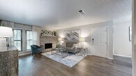 This single-floor residence offers a thoughtfully designed layout that balances comfort and functionality across its living spaces. The spacious living room serves as the heart of the home, anchored by a classic brick fireplace and framed by wood-look flooring that extends throughout. Large windows invite natural light, creating a warm and welcoming ambiance.

Adjacent to the living area, a dedicated dining space accommodates a full-sized table, making it well-suited for everyday meals and entertaining alike. The galley-style kitchen is equipped with stainless steel appliances, including a range, microwave, refrigerator, and dishwasher, complemented by granite countertops, a subway tile backsplash, and gray shaker-style cabinetry.

The primary bedroom is generously sized with sliding door access and connects to a well-appointed vanity area featuring granite counters, dual sinks, and a large mirror with bright overhead lighting. An adjacent closet provides convenient storage. A secondary bedroom offers its own closet space and maintains the same wood-look flooring found throughout the residence.

Textured ceilings are consistent across the home, lending a cohesive architectural character, while the neutral gray and white palette throughout creates a clean, modern aesthetic that is both versatile and inviting.