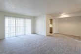 Located at 3600 N Midland Dr in Midland, Texas, this single-story residence offers a functional and comfortable layout designed for everyday living. The open living area is generously sized, featuring neutral wall-to-wall carpeting, a textured ceiling, and a large sliding glass door dressed with vertical blinds that fills the room with natural light and provides outdoor access. A pass-through opening connects the living space to the kitchen, enhancing the sense of openness throughout. The galley-style kitchen is efficiently arranged with warm wood cabinetry, white countertops, and light hardwood-style flooring. It is equipped with a full suite of appliances including a stainless steel refrigerator, an over-the-range microwave, and an electric range, with ample upper and lower cabinet storage on both sides. The bedroom is a well-proportioned, carpeted room featuring a ceiling fan with light fixture and a window that brings in natural light. The bathroom is clean and straightforward, featuring a tub-shower combination, a toilet, a wood-cabinet vanity with countertop, and hardwood-style flooring. Overall, the space presents a neutral, move-in ready aesthetic with a practical layout suited for comfortable day-to-day living in West Texas.