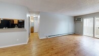 Located at 1250 S Clermont St in Denver, CO, this one-bedroom, two-bathroom unit at Infinity Flats offers a functional and comfortable single-floor layout. The living room is a highlight of the space, featuring warm wood-style flooring, a tile-surround fireplace, and a sliding glass door that opens onto a private balcony, filling the room with natural light. Baseboard heating runs along the walls, providing efficient warmth throughout the main living areas. The dining area flows naturally from the living space, maintaining the same hardwood-style flooring for a cohesive feel. The kitchen is well-equipped with warm wood cabinetry, tile backsplash, stone-toned countertops, and black appliances including a range, dishwasher, refrigerator, and microwave. A hallway connects the main living areas to the private bedroom, which features plush carpeting, a large closet with double panel doors, a window offering natural light, and baseboard heating. Two full bathrooms serve the unit, one of which includes a tiled tub-shower combination. Two closets provide ample storage throughout. Textured ceilings are consistent across the unit, complementing the neutral gray wall tones for a clean, move-in ready aesthetic.