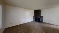 Located in University Place, Washington, this one-bedroom, one-bathroom unit offers a practical and well-organized single-floor layout. The combined kitchen and living room serves as the heart of the home, with the living area featuring wall-to-wall carpeting, a textured ceiling, and a striking corner fireplace clad in natural stone with a dark wood surround — a functional and eye-catching focal point. Large windows allow natural light to filter in, offering views of surrounding greenery and a balcony railing visible from inside. The kitchen is equipped with warm-toned wood cabinetry, ample upper and lower storage, light countertops in an L-shaped configuration, a stainless steel sink, and a dishwasher. Light wood-style flooring runs throughout the kitchen area. The bedroom is a comfortable, carpeted room with a window that brings in natural light and includes a baseboard heating unit. A dedicated closet provides organized storage. The bathroom features a full tub-shower combination with chrome fixtures, a toilet, a towel bar, and light wood-style flooring. Textured ceilings are consistent throughout, and the neutral wall palette creates a clean, move-in-ready atmosphere throughout the space.