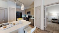 This single-floor residence in Oklahoma City, OK (73104) offers a well-designed layout with multiple bedrooms, bathrooms, and a contemporary aesthetic throughout. The kitchen is a standout feature, showcasing light wood cabinetry, dark contrasting lower cabinets, a white quartz island with seating, black appliances including a refrigerator, range, and microwave, and track lighting that illuminates the wood-look flooring beneath. The open sightlines from the kitchen into the living and dining areas create a seamless flow.

Each bedroom is carpeted and benefits from natural light through window blinds. The primary bedroom is generously proportioned, featuring a ceiling fan, large windows with sheer drapes, and ample wall space. A secondary bedroom includes a ceiling fan and vibrant natural light, while a third bedroom offers a cozy, well-lit atmosphere.

The bathrooms are finished with large-format tile flooring, wood-toned vanity cabinetry, white countertops, and well-lit mirrors. One bathroom includes a walk-in closet with built-in shelving and hanging rods, providing excellent storage. A tub-shower combination and additional wall-mounted cabinetry complete the bathrooms' functional design. Overall, the space presents a clean, modern living environment suited for comfortable everyday living.