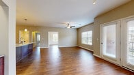Located at 1501 NW 38th St in Kansas City, Missouri, this single-story residence offers a thoughtfully designed layout with a cohesive blend of practical finishes and comfortable living spaces throughout.

The expansive main living area serves as the heart of the home, showcasing rich hardwood-style flooring, neutral warm-toned walls, and a ceiling fan overhead. Multiple windows fitted with white blinds allow generous natural light to fill the space, while French doors provide additional access to the outdoors. The open layout flows seamlessly into a secondary living or dining area, offering flexible use of the generous floor plan.

The kitchen is a standout feature, centered around a large island with a granite countertop and pendant lighting above. Rich dark-stained cabinetry lines the walls, complemented by a subway tile backsplash and stainless steel appliances. A dedicated laundry area is conveniently accessible nearby.

The bedrooms are carpeted for comfort, each featuring ceiling fans and ample natural light from multiple windows. The primary bathroom includes a dual-sink vanity with granite countertops, dark wood cabinetry, a tiled tub and shower combination, and an elegantly arched accent. A secondary bathroom offers similar granite and cabinetry finishes. A spacious walk-in closet with wire shelving provides excellent storage capacity.
