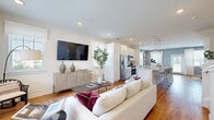 Located at 242 Roscommon Dr in Exton, PA, this two-story home offers three bedrooms and three full bathrooms across a well-organized layout. The main floor hosts the primary living spaces, where an open-concept design connects the living room, kitchen, and dining room in a seamless, light-filled arrangement. Warm hardwood flooring runs throughout, complemented by recessed lighting and large windows that invite natural light. The living room features multiple windows with neighborhood views, creating a bright and airy atmosphere. The kitchen is equipped with stainless steel appliances, white shaker cabinetry, a quartz waterfall island with bar seating, and pendant lighting overhead. The adjacent dining area accommodates a full-size table beneath natural light. A staircase leads to the upper floor, which contains the three bedrooms and additional bathrooms. The generously sized primary bedroom includes a walk-in closet with wire shelving and carpet flooring. The bathrooms are finished with white subway tile, tile flooring, white vanities, and clean, modern fixtures throughout. Two hallways connect the upper-level rooms efficiently. The home's neutral palette and consistent finishes give the overall space a cohesive, contemporary character.
