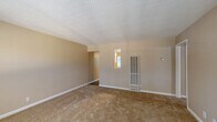 Located at 2400 Arden Way in the Arden-Arcade neighborhood of Sacramento, CA, this single-story, one-bedroom, one-bathroom unit offers a practical and comfortable layout. The kitchen is a standout feature, outfitted with white shaker-style cabinetry, granite-look countertops, a gas range, over-the-range microwave, and a full-size refrigerator. Wood-style vinyl flooring runs throughout the kitchen and dining area, which is brightened by a large window overlooking lush greenery and a ceiling fan overhead. The living area and bedroom feature neutral-toned carpet, warm beige walls, and textured ceilings, creating a cozy, understated ambiance. The bedroom is a comfortable size with a window that frames views of surrounding trees, filling the space with natural light. The hallway connects the main living spaces and includes two doors, one of which serves as the unit's entry. The bathroom features a full tub-shower combo with white tile surround and brushed nickel fixtures. Throughout the unit, white trim and baseboards provide clean, crisp contrast to the warm wall tones, contributing to a cohesive and move-in-ready aesthetic.