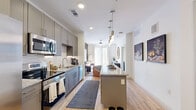 This thoughtfully designed one-bedroom residence offers a efficient and stylish single-floor layout that maximizes every square foot. The open-concept kitchen and living area serves as the heart of the home, featuring gray shaker-style cabinetry, granite countertops, a hexagonal tile backsplash, and a full suite of stainless steel appliances including a side-by-side refrigerator, range, microwave, and dishwasher. A central kitchen island with pendant lighting provides additional prep space and casual seating. Light wood-style flooring flows throughout the main living areas, complementing the bright, neutral color palette. The living room offers a bold accent wall, large floor-to-ceiling windows, and French doors that invite abundant natural light. The spacious primary bedroom features soft carpet, a calming sage green accent wall, and wide windows dressed with layered curtains for privacy and light control. The en-suite bathroom is appointed with a granite-topped vanity, gray cabinetry, and modern brushed nickel fixtures. The unit also includes two closets, a dedicated laundry area, and an unclassified bonus room, rounding out a practical and polished living space.