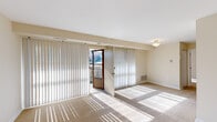 This one-bedroom, one-bathroom unit offers a thoughtfully arranged single-floor layout that maximizes every square foot of its compact footprint. The combined living and dining area serves as the heart of the unit, featuring neutral-toned carpet, a flush-mount ceiling light, and large sliding glass doors dressed with vertical blinds that open to an outdoor balcony. The balcony access floods the space with natural light and provides outdoor views of surrounding greenery.

The kitchen is efficiently designed with warm wood-toned cabinetry, light speckled countertops, a double sink, and white appliances including a range and refrigerator. Dark wood-style vinyl flooring grounds the kitchen area, providing a clean contrast to the carpeted living spaces. An open shelving unit adjacent to the kitchen offers convenient pantry storage.

The bedroom is a comfortable, well-proportioned retreat featuring soft carpet, a ceiling fan with integrated lighting, and a window that invites natural light. Multiple closets — including a walk-in — provide ample storage. The bathroom is clean and straightforward, featuring a tub-shower combination with white tile surround, a vanity with under-sink cabinet, a medicine cabinet mirror, and wood-style vinyl flooring. Three additional closets throughout the unit further enhance the overall storage capacity of this practical and livable space.
