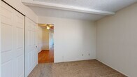 Located at 108 Heile Dr in Reading, Ohio, this single-floor unit offers a practical and comfortable layout across several well-defined living spaces. The galley-style kitchen is equipped with warm wood cabinetry, laminate countertops, a double-basin sink, and white appliances including a range and refrigerator. A window above the counter allows natural light to brighten the space, while hardwood-style flooring adds a clean, durable finish underfoot. The living and bedroom areas feature wall-to-wall carpet and neutral-toned walls, creating a calm and versatile environment. Exposed ceiling beams add a subtle architectural detail to select rooms. Multiple windows fitted with blinds provide views of the surrounding greenery and allow ample natural light throughout. Several rooms include wall-mounted air conditioning units and baseboard heating, offering year-round climate control. Closet space is available in the bedrooms, with sliding and hinged door configurations. The bathroom is finished with light tile flooring and wall tile surrounding a full bathtub with shower. A window provides ventilation, and a vanity with storage completes the space. Textured ceilings are present throughout, and the overall layout—as seen in the overhead model view—flows in a connected, linear arrangement suited for everyday living.