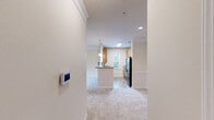 Located at Ashton Pointe in Port Royal, South Carolina, this one-bedroom, one-bathroom residence offers a well-planned single-floor layout designed for comfortable everyday living. The combined kitchen and living room serves as the heart of the home, with the living area featuring plush carpeting, crown molding, a ceiling fan, and sliding glass doors that open to a private balcony with lush outdoor views. The kitchen is a functional galley-style space outfitted with light wood cabinetry, ample counter space, wood-look luxury vinyl flooring, and black appliances including a range, built-in microwave, dishwasher, and refrigerator. A peninsula with pendant lighting provides a natural transition between the kitchen and living area. The bedroom is a comfortable retreat with carpet flooring, a ceiling fan, a window allowing natural light, and a dedicated closet. The full bathroom includes warm wood-toned cabinetry, a white countertop vanity, a tub/shower combination, and matching wood-look flooring. A dedicated laundry area accommodates a full-size washer and dryer with overhead shelving for added storage. The hallway connects all spaces efficiently, completing this well-appointed Port Royal residence.