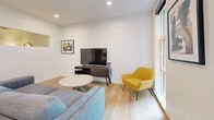 Located at 955 Bannock St in Denver's vibrant Baker neighborhood, this thoughtfully designed single-floor unit offers a clean, modern aesthetic across its well-organized layout. The open-concept kitchen and living area forms the heart of the space, where light wood-style flooring and crisp white walls create a bright, welcoming atmosphere. The kitchen is outfitted with full-height white cabinetry, stainless steel appliances including a refrigerator, range, and over-the-range microwave, a deep sink with a matte black faucet, and open shelving for added functionality. Pendant lighting with bold black fixtures illuminates the dining area, which comfortably fits a four-seat table. The adjoining living room benefits from large windows that invite natural light and urban views, recessed ceiling lighting, and a versatile layout accommodating a sofa, accent chair, coffee table, and media console. A hallway connects the main living area to the full bathroom, which features a tub-shower combination with subway tile surround, a marble-topped vanity with white cabinetry and matte black hardware, a large framed mirror, and clean white tile flooring. The unit's cohesive modern design, quality finishes, and efficient use of space make it a well-appointed urban residence.