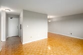 Located on the fifth floor at 6 24th St in Toronto's Mimico neighbourhood, this one-bedroom, one-bathroom unit offers a thoughtfully organized layout across a single floor. The living room is the largest area of the unit, featuring warm parquet flooring in a classic basket-weave pattern, neutral grey walls, and a large sliding glass door that opens onto a private balcony with open city views. A secondary window along the adjacent wall enhances natural light and ventilation, with a baseboard radiator ensuring comfortable heating. The galley-style kitchen is efficiently designed with white cabinetry, brushed nickel hardware, a subway tile backsplash, and dark laminate countertops. White appliances including a refrigerator and electric stove are integrated seamlessly. Tile flooring runs the length of the kitchen, which connects directly to the hallway. The bedroom is a comfortable size, continuing the parquet flooring, and includes a built-in closet. The bathroom features a full soaker tub with tiled surround in neutral tones, a vanity with dark cabinetry, and tile flooring. Throughout, the unit maintains a clean, neutral palette that offers a practical and move-in-ready living environment.