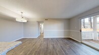 Located at 2340 Spring House Ln in Augusta, Georgia, this 2-bedroom, 1-bathroom single-story residence offers a practical and well-organized layout with consistent, modern finishes throughout. The open-concept living, dining, and kitchen area forms the heart of the home, where rich wood-look flooring and neutral gray walls create a clean, cohesive aesthetic. A tile-surround fireplace anchors the living area, adding both character and warmth. A peninsula with light stone-look countertops connects the kitchen to the living space, providing additional prep and dining surface. The kitchen itself is galley-style, outfitted with white cabinetry, stone-look countertops, stainless steel appliances, and hardwood-style flooring. A sliding glass door in the dining area opens to an outdoor balcony, inviting natural light and exterior views of surrounding greenery. The two bedrooms feature plush carpeting and neutral walls; the primary bedroom is generously sized and includes a window with outdoor views, while the second bedroom connects conveniently to the hallway. A dedicated closet and full bathroom complete the floor plan, which is organized efficiently via a central hallway.