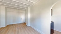 Located in Chicago's desirable Gold Coast neighborhood, this 1-bedroom, 1-bathroom unit at 1211 North La Salle Drive offers a well-designed layout across a single floor. A defining architectural feature throughout the living spaces is the striking white coffered ceiling, which adds visual depth and a classic character to the interior. Light wood laminate flooring runs throughout, creating a clean and cohesive aesthetic.

The combined living and dining area is bright, with windows that frame urban city views and allow natural light to fill the room. A baseboard heating system and window AC unit ensure year-round comfort. The galley-style kitchen is efficiently arranged, featuring stainless steel appliances including a refrigerator, electric range, and over-the-range microwave, complemented by white cabinetry and light countertops with a subtle backsplash.

The spacious bedroom includes a generous closet, with an additional closet accessible from the hallway for ample storage. The bathroom is tastefully updated, showcasing floor-to-ceiling white subway tile surrounding a soaking tub and shower, a warm walnut vanity with white countertop, and elegant brushed gold fixtures. A dedicated laundry area with a washer and built-in shelving adds everyday convenience to this well-appointed urban home.