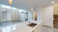 This contemporary two-floor residence is designed with a clean, minimalist aesthetic throughout. The open-concept kitchen serves as the heart of the main level, featuring a large white quartz island with an undermount stainless steel sink, pendant lighting, high-gloss white cabinetry, and a full suite of stainless steel appliances including a refrigerator, electric range, and built-in microwave. A subway tile backsplash adds texture, while light wood-look flooring runs seamlessly throughout the space.

The living area adjoins the kitchen and is bathed in natural light from generous windows, offering views of the surrounding streetscape. A wall-mounted split system provides climate control on the main floor, while baseboard heaters are present in the bedrooms. A staircase connects both levels, with a bright upper landing featuring large windows.

Multiple bedrooms feature neutral grey walls, light wood flooring, and built-in sliding-door closets with shelving systems, offering practical storage solutions. The bathrooms are consistently finished with warm wood-toned vanities, grey quartz countertops, undermount sinks, large mirrors, and fully tiled tub-shower combinations enclosed by glass shower doors. The overall ambiance is bright, clean, and modern throughout.