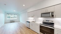 Located at 411 SE Ellsworth Rd in Vancouver, Washington, this single-floor unit offers a clean, modern aesthetic throughout. The open-concept layout seamlessly connects the kitchen and living area, creating an efficient and welcoming atmosphere. Light hardwood-style flooring extends across the entire space, complementing the crisp white walls and recessed lighting that keep the interior feeling bright and airy.

The kitchen is well-appointed with flat-front gray cabinetry, white quartz countertops, a classic subway tile backsplash, and a full suite of stainless steel appliances, including an electric range, over-the-range microwave, dishwasher, and refrigerator. The open living area adjacent to the kitchen provides a versatile space bathed in natural light from a large window.

The bedroom is a calm, neutral retreat featuring a ceiling fan, a window offering views of the surrounding neighborhood, and the same warm hardwood-style flooring found throughout the unit.

The bathroom is finished in a consistent modern style, with white cabinetry, a large vanity mirror, quartz countertop, and a full tub-shower combination outfitted with brushed nickel fixtures. The overall design of the space prioritizes clean lines, functionality, and a light, contemporary feel.