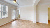 Located at 9500 Muirfield Club Rd in Raleigh, NC, this single-floor, three-bedroom, two-bathroom home offers a well-designed layout with a warm, neutral color palette throughout. The open-concept kitchen and living area serves as the heart of the home, featuring rich warm-toned cabinetry, granite countertops, stainless steel appliances including a refrigerator, range, microwave, and dishwasher, and light hardwood-style flooring that extends into the living and dining spaces. Crown molding and a textured ceiling add architectural character to the main living area, which benefits from large windows that invite abundant natural light and views of the surrounding neighborhood. The spacious primary bedroom is outfitted with plush carpeting, a ceiling fan, and a generously sized walk-in closet with wire shelving for ample storage. Two additional bedrooms also feature ceiling fans and soft carpeting, with one room offering a large window with outdoor views. Both bathrooms are finished with warm wood-tone vanities, granite countertops, and tub-shower combinations accented by a classic white and taupe checkered tile border. A welcoming entryway with crown molding and hardwood-style flooring provides a polished first impression upon arrival.