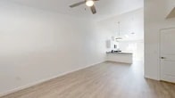 Located at 11940 Camel Rock Dr in Reno, NV, this efficiently designed single-story home offers a clean, modern aesthetic throughout. The open-concept living and kitchen area is anchored by light wood-look flooring, crisp white walls, and a ceiling fan, creating a bright and airy atmosphere. The kitchen is a functional highlight, featuring white shaker cabinetry, dark countertops, stainless steel appliances including a range, over-the-range microwave, and refrigerator, as well as a peninsula with a built-in sink that provides additional prep space. A skylight above the kitchen fills the area with natural light, while a sliding glass door opens directly to a private, fenced outdoor patio. In-unit stacked laundry is conveniently tucked within the kitchen space. The bedroom is a comfortable retreat with plush carpeting and a window that allows natural light. The bathroom is well-appointed with a vanity featuring a stone-topped countertop, white cabinetry, and a full tub-shower combination. A hallway connects the main living areas seamlessly. The attached single-car garage provides secure parking and additional storage. Throughout, the home maintains a consistent, modern palette that is clean and move-in ready.