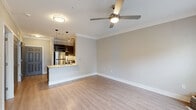 This thoughtfully designed 1-bedroom, 1-bathroom unit offers a comfortable and functional layout across a single floor. The open-concept living and kitchen area serves as the heart of the home, featuring light hardwood-style flooring, crown molding, and a ceiling fan that enhances the airy feel of the space. The kitchen is equipped with stainless steel appliances, rich dark cabinetry, granite countertops, a tile backsplash, and a breakfast bar that flows seamlessly into the living area. Track lighting overhead and pendant lights above the bar add a polished touch.

The bedroom is generously proportioned, offering two windows with blinds that invite natural light and provide views of the surrounding greenery. Crown molding and a ceiling fan continue the cohesive design language throughout.

The bathroom features a combination tub and shower with tile surround, hardwood-style flooring, and a granite-topped vanity with dark cabinetry, maintaining the upscale aesthetic found throughout the unit.

A dedicated laundry room houses a full-size washer and dryer with wire shelving above for added storage. The unit also includes an attached garage, providing secure parking and additional storage space. A hallway connects the main living areas, completing this efficient and well-finished floor plan.