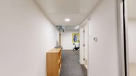 Located at 4603 Minnehaha Ave in Minneapolis, MN, this single-level fitness facility offers a thoughtfully designed workout environment spread across three distinct zones. The space is finished with crisp white walls and consistent recessed and linear LED lighting throughout, creating a bright, clean, and energizing atmosphere.

The cardio area features rubber flooring and houses a lineup of machines including treadmills, stationary bikes, a rowing machine, and elliptical trainers, all arranged along the perimeter for ease of movement. A wall-mounted television adds to the workout experience. Vibrant artwork along the walls adds a touch of character to the space.

The strength training room is outfitted with professional-grade Rogue equipment, including a wall-mounted power rack with cable attachments and gymnastic rings, a flat bench, and a full dumbbell rack. Rubber flooring provides safety and durability underfoot, while a wall-mounted display screen keeps users engaged.

A flexible open workout room features light hardwood-style flooring, floor-to-ceiling mirrors that visually expand the space, and ample room for stretching, yoga, or bodyweight exercises. Yoga mats, balance tools, and a stability ball are available within this area.

A connecting corridor with built-in storage shelving ties the zones together, giving the facility a cohesive and functional flow suited for diverse fitness needs.