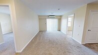 Located at 1195 Western Ave in Beaver, PA, this single-floor, 2-bedroom, 1-bathroom residence offers a practical and comfortable layout designed for everyday living. The open living area features neutral-toned carpet, a wall-mounted mini-split HVAC unit, and a sliding glass door with vertical blinds that invites natural light into the space. The kitchen is a standout feature, showcasing rich warm-toned cabinetry, granite-style countertops, stainless steel appliances including a refrigerator, electric range, microwave, and dishwasher, along with a peninsula that provides additional counter space and separates the kitchen from the living area. Tile flooring runs throughout the kitchen. The two bedrooms are carpeted and finished in soft, neutral tones. The primary bedroom offers a generous footprint with a double-door closet, while the second bedroom features a window with outdoor views, bringing in natural light. The bathroom is well-equipped, featuring a walk-in glass shower, a warm wood-toned vanity with a large mirror, tile flooring, and accessibility grab bars. A stacked washer and dryer unit is conveniently located within the bathroom, adding in-unit laundry functionality. Clean white trim and consistent neutral wall tones give the entire residence a cohesive and move-in-ready feel.